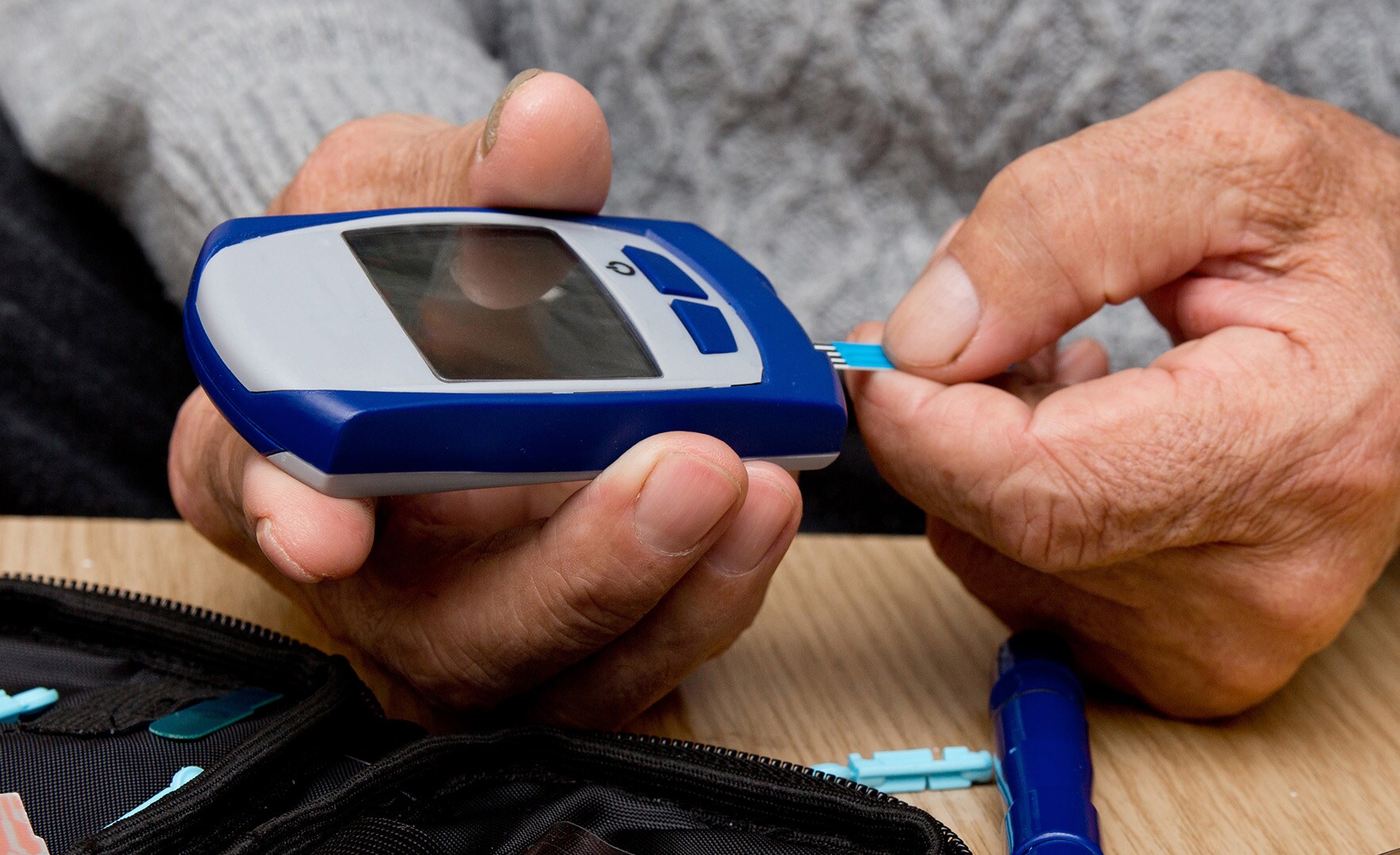 Man's hands using diabetic test strip machine