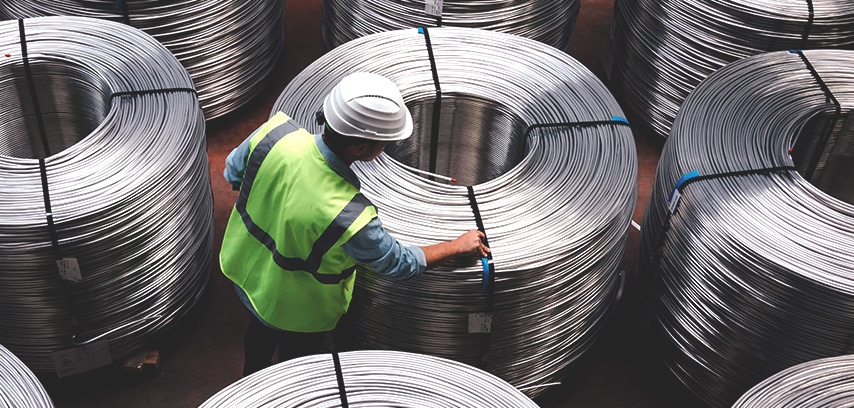 Worker checking coils of metal