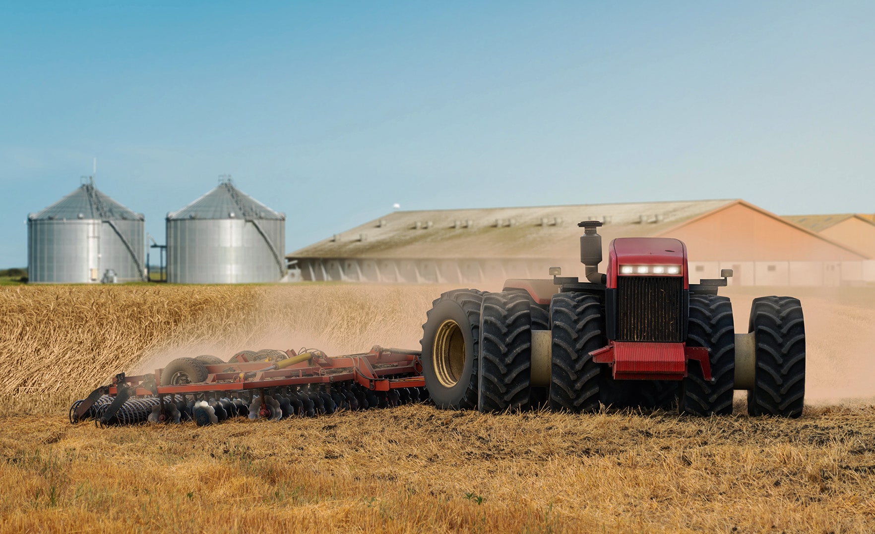 Farm combine in field with silos in background