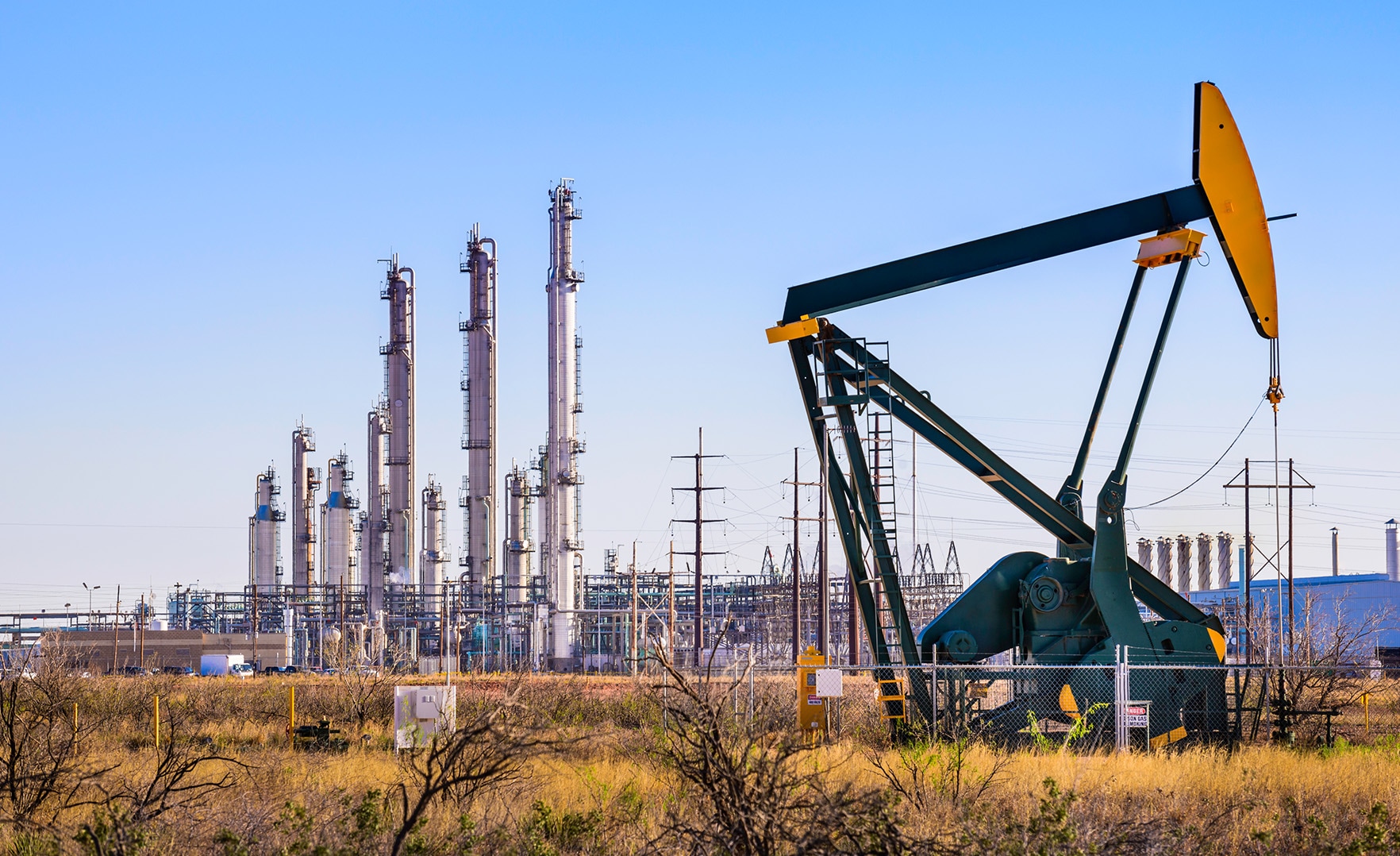 Yellow oil pump with refinery in background