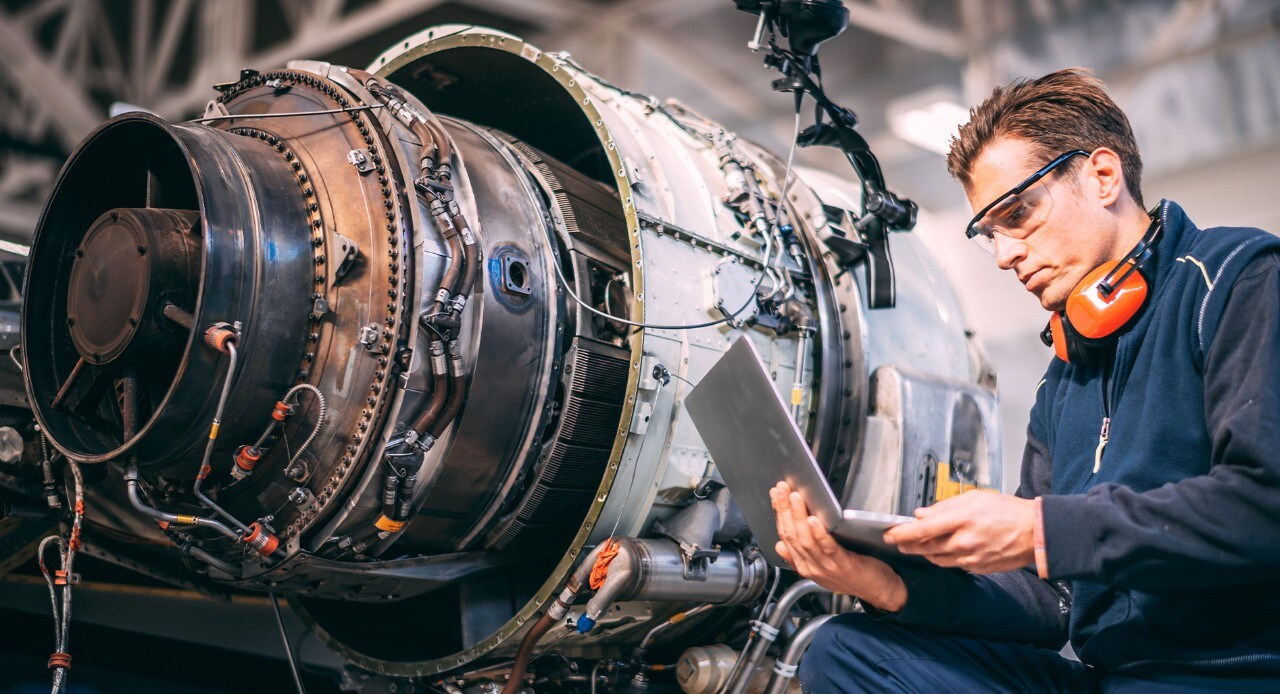 Mechanic sitting next to plane engine